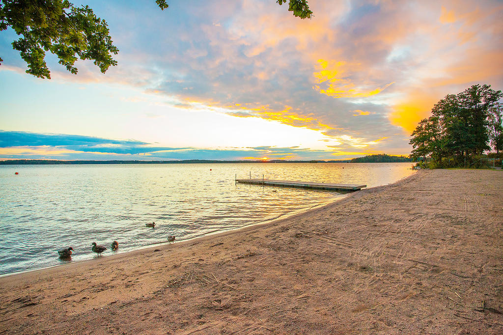 Vackert bad i området med sandstrand, gräsytor och badbryggor