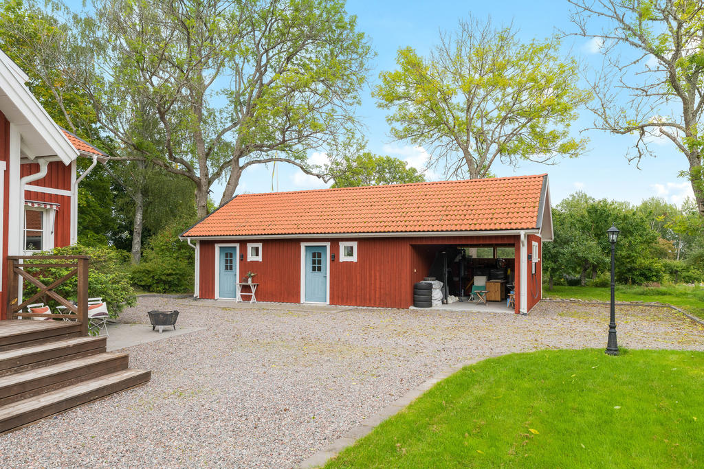 Carport med elbilsladdare, förråd och gästhus.