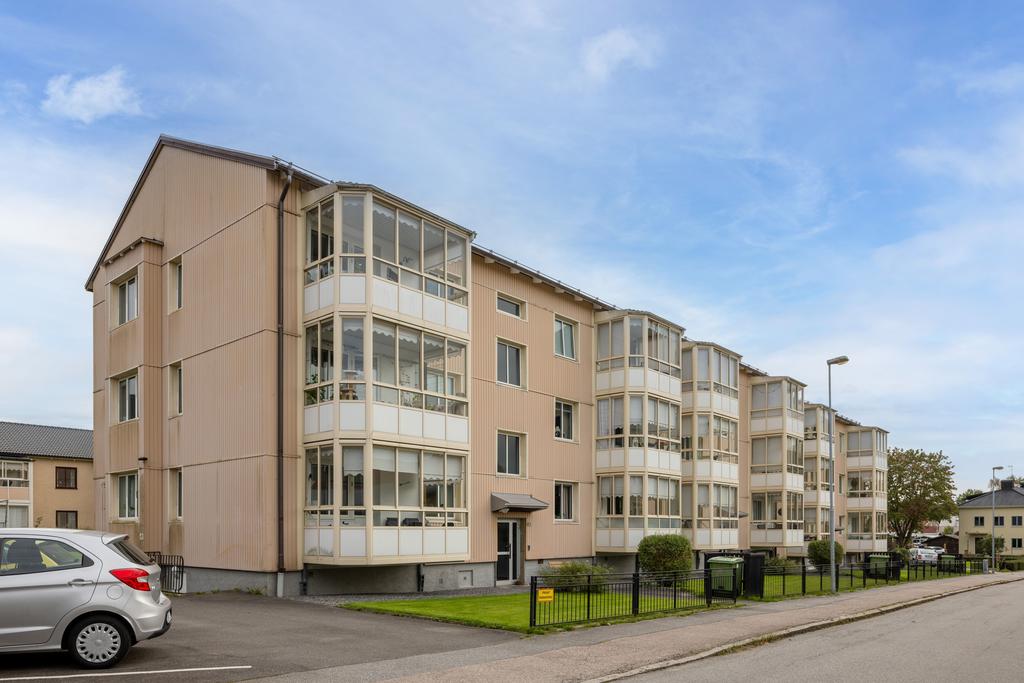 Brf Klockegård med tillhörande parkeringsplatser på vänster sida om huset.