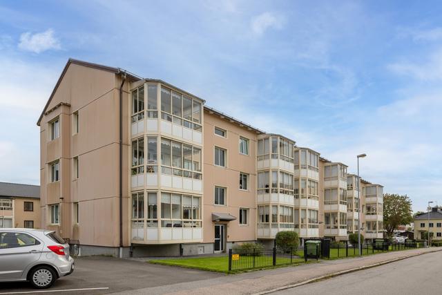 Brf Klockegård med tillhörande parkeringsplatser på vänster sida om huset.