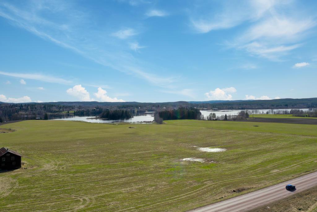 Drönarbild med vy över riksväg 301 samt bakomliggande åkrar och sjön Viksjön. 