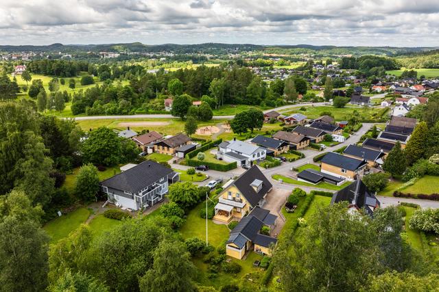 Huset med altan och balkong in mot trädgården. Översikt över området och golfbanan.