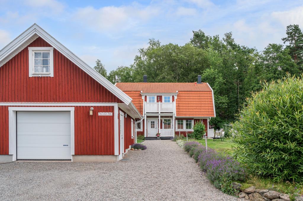 Lantdröm med grusad entré och röda hus.