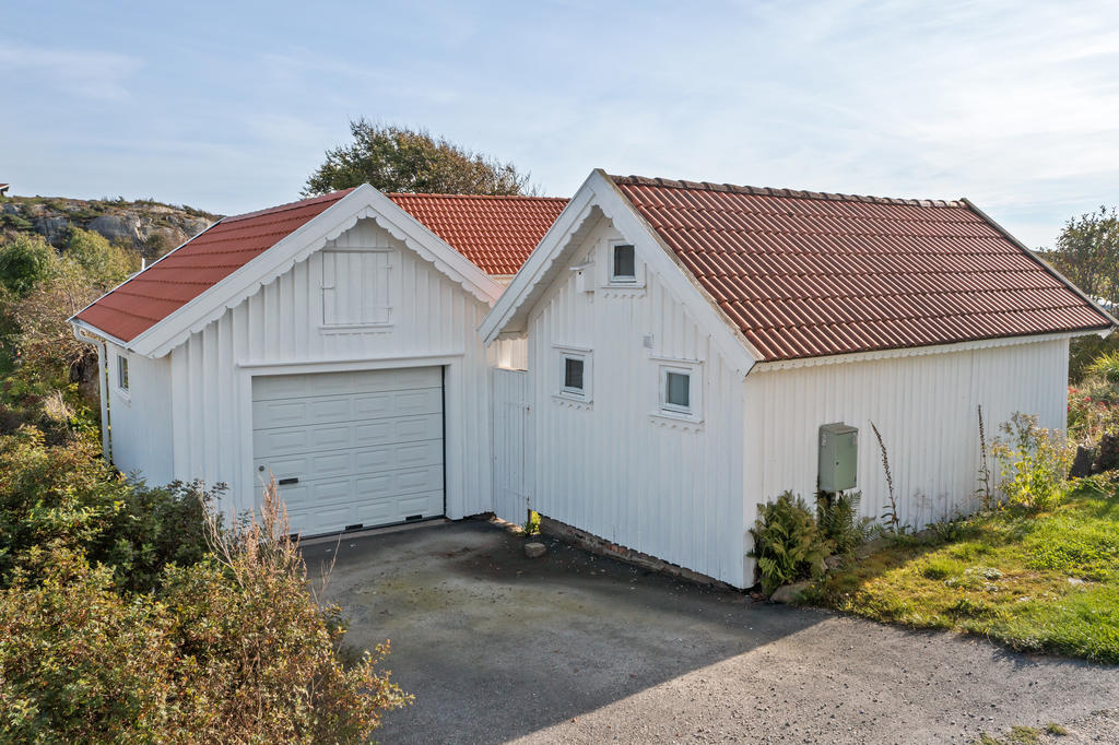 Garage med parkeringsplats och gästhus i bild.